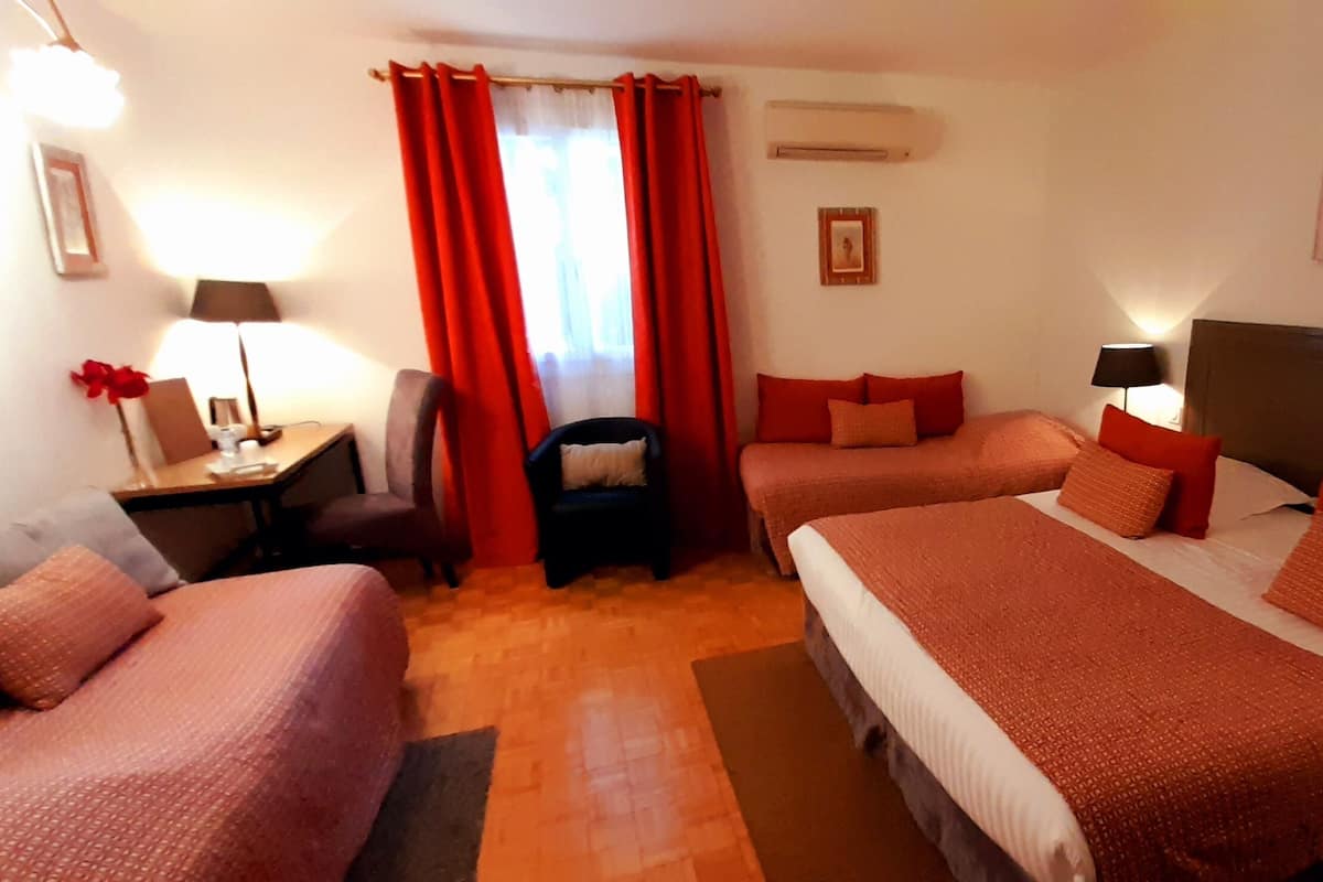 A hotel room with two beds, a desk, a chair, and a nightstand with lamps.
