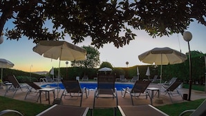 A poolside area with lounge chairs and umbrellas, a swimming pool, and a view of the sky. - Hotel Lombiña (Puebla del Caraminal)