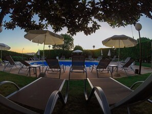 Una piscina al aire libre, sillones reclinables de piscina