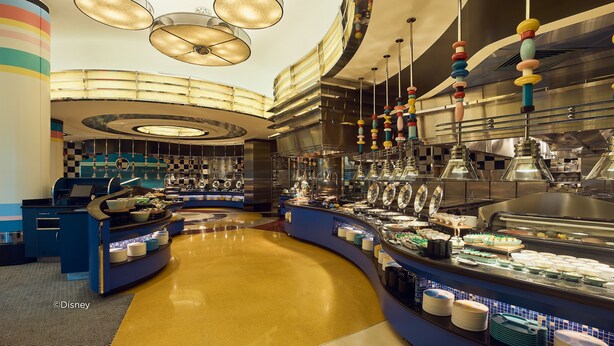 A modern hotel lobby with a central reception desk, a curved counter with food displays, and a check-in area. - Disney's Hollywood Hotel (Lantau)