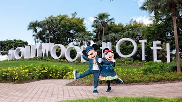 Mickey and Minnie Mouse posing in front of a large sign with the text "Disney World".