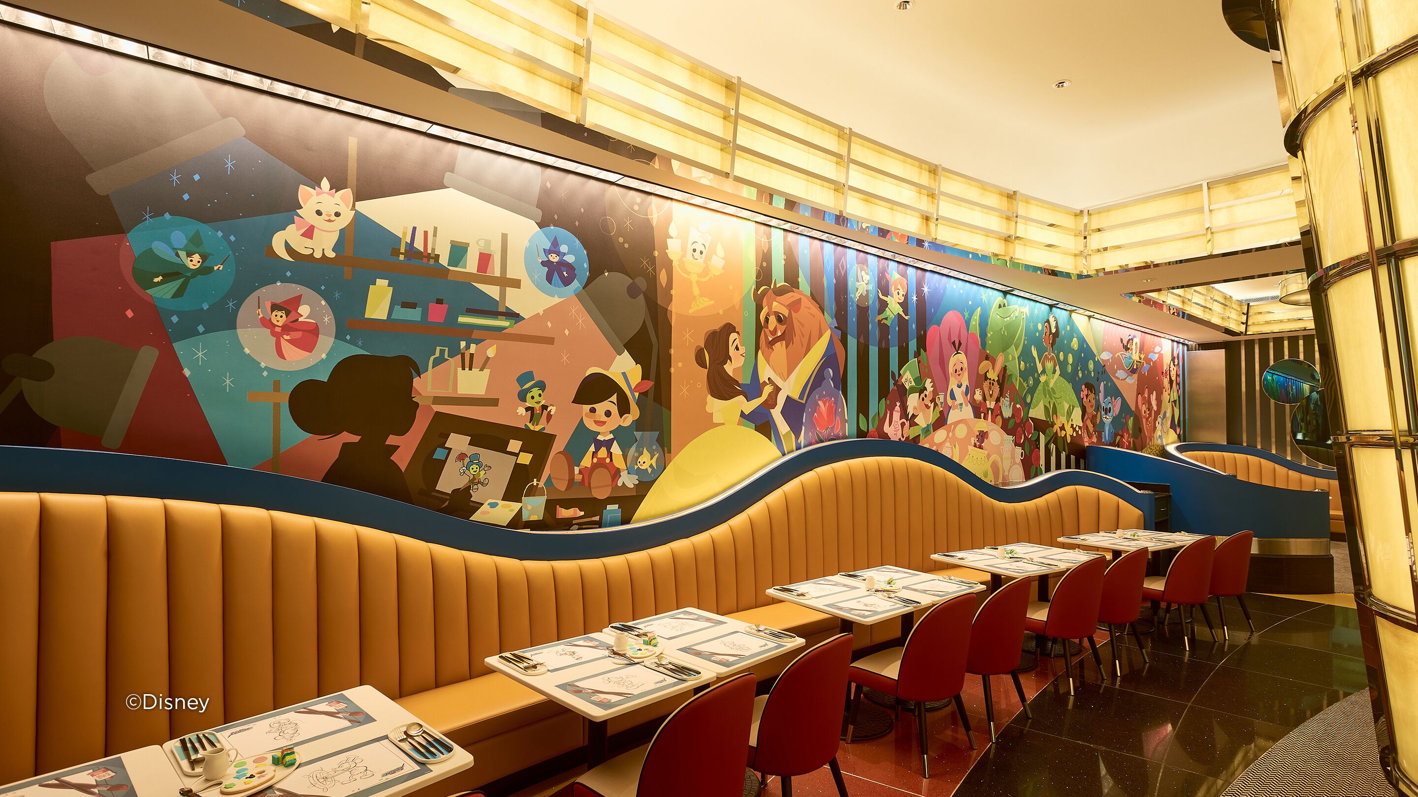 Een restaurant met zitplaatsen in cabines en aan tafels, met een kleurrijke muurschildering met tekenfilmfiguren.