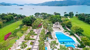 A resort with a large pool, palm trees, and a view of the ocean. - Disney's Hollywood Hotel (Lantau)