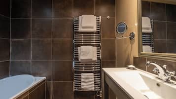 A modern bathroom with a bathtub, a large sink, and a towel rack with multiple towels.