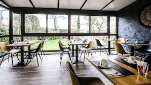 A modern dining area with large windows, multiple tables, and chairs. - Hôtel Des Cèdres (Orléans)