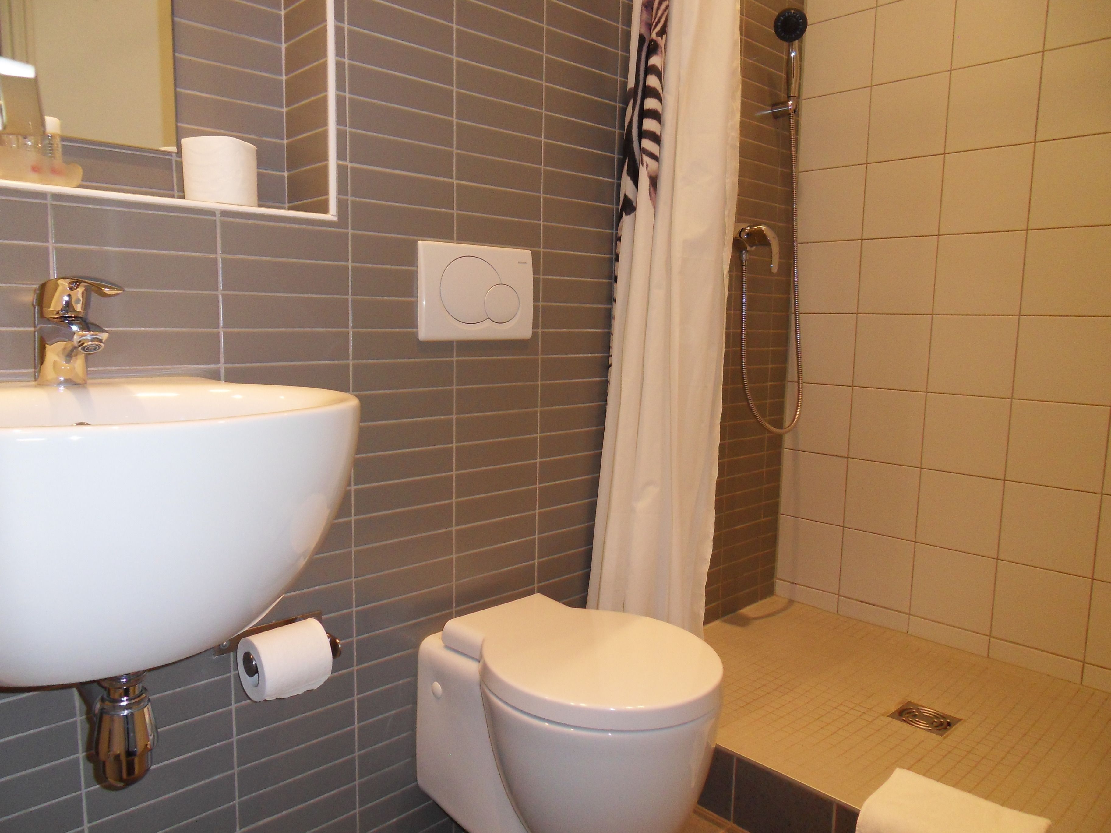 Et badeværelse med håndvask, toilet og brusebad.