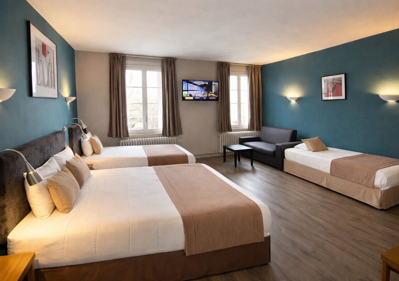 A hotel room with two beds, a television, and a sofa.