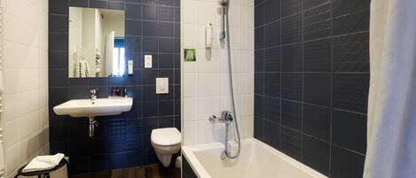 Een moderne badkamer met een wit wastafelmeubel, toilet en bad.
