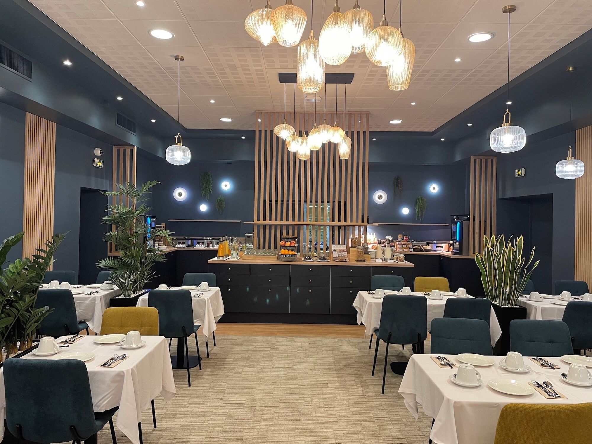 Un restaurant doté de nombreuses tables, d’un bar central et de luminaires suspendus.