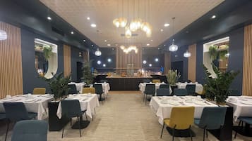 A restaurant with round tables, chairs, and hanging light fixtures.