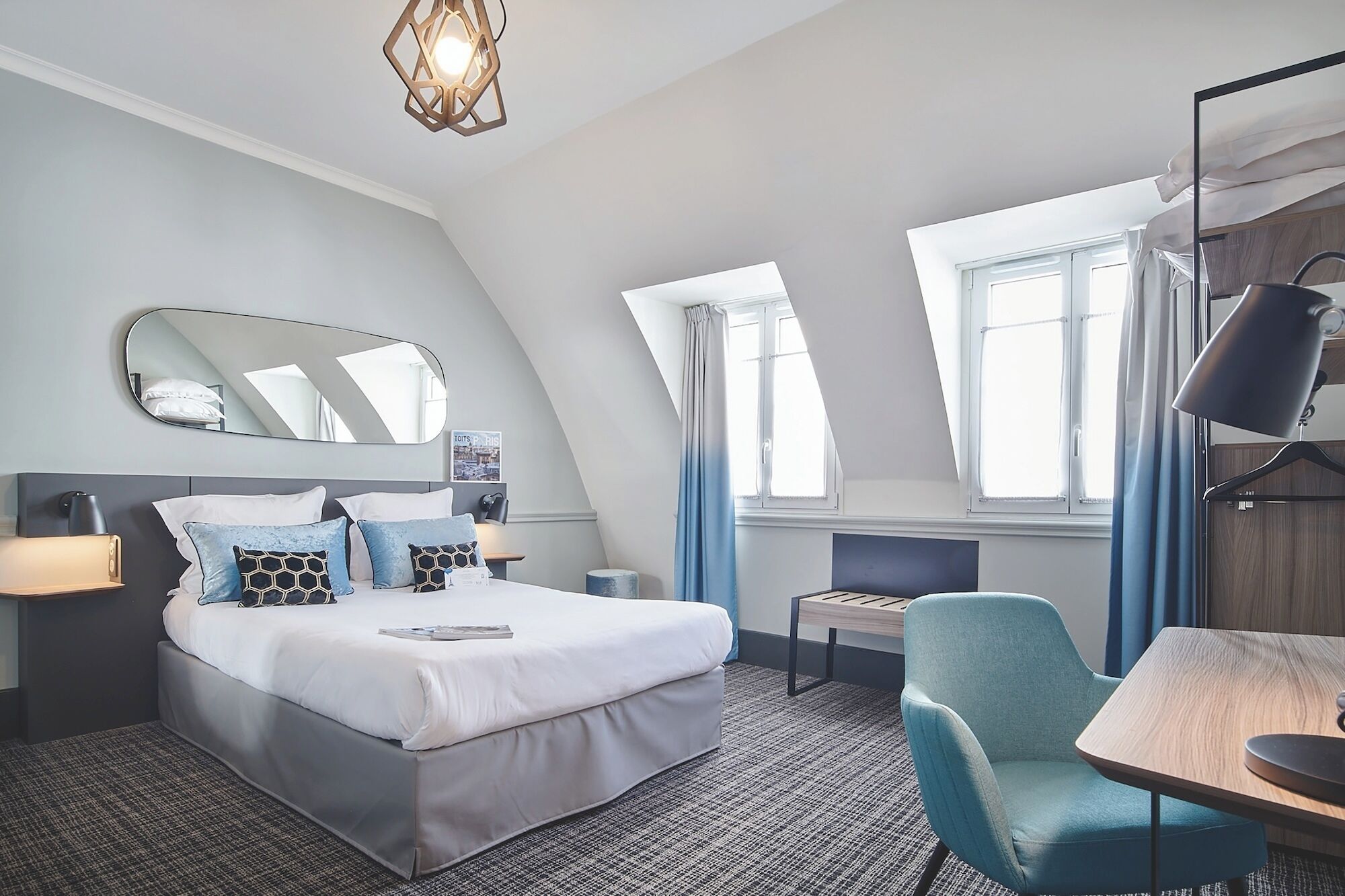 Ein modernes Hotelzimmer mit Bett, Nachttisch, Lampe, Stuhl und Schreibtisch mit einer Lampe.