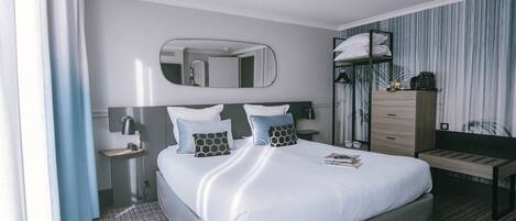 Una habitación de hotel con cama, mesita de noche, lámpara, cómoda, espejo y cortinas.
