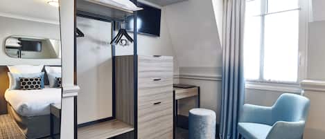 Habitación de hotel compacta con literas, un escritorio, una silla y un amplio ventanal con cortinas.