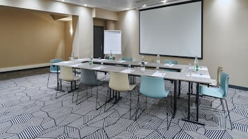 A conference room with a long table, chairs, a projector screen, and a whiteboard.