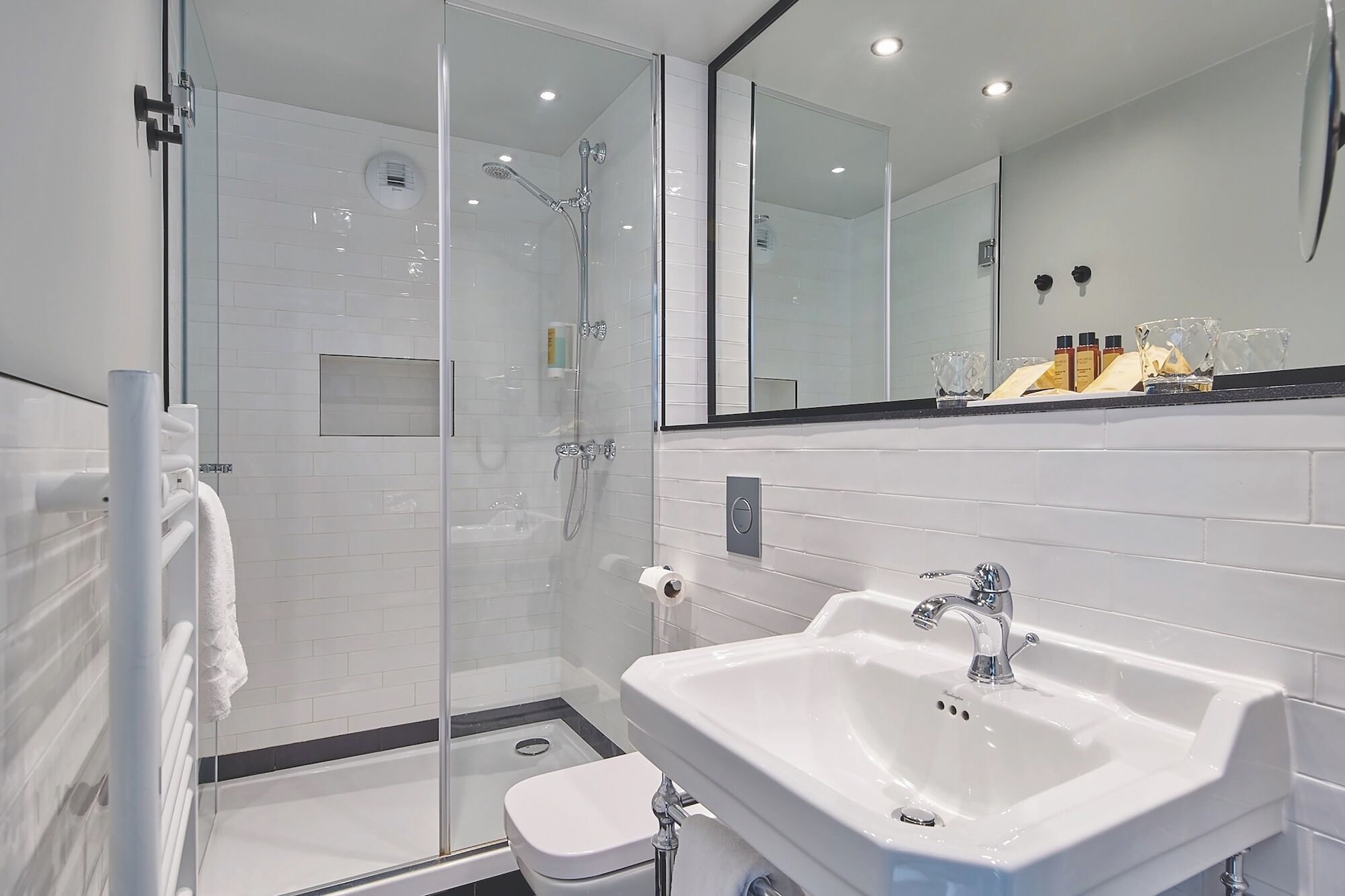 A modern bathroom with a glass shower enclosure, a white sink, and a large mirror.