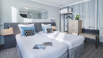 Une chambre d’hôtel avec un lit double, des tables de chevet, un miroir, une commode et une fenêtre avec des rideaux.