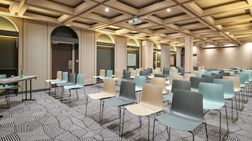 A conference room with rows of chairs, tables, and a patterned carpet.