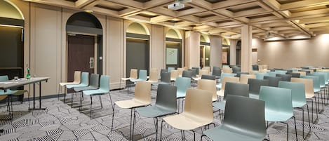 Ein Konferenzraum mit Reihen von Stühlen, Tischen und einem gemusterten Teppich.