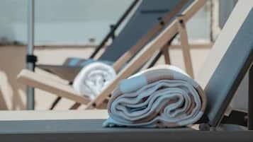 A row of sun loungers with towels neatly rolled up on them.