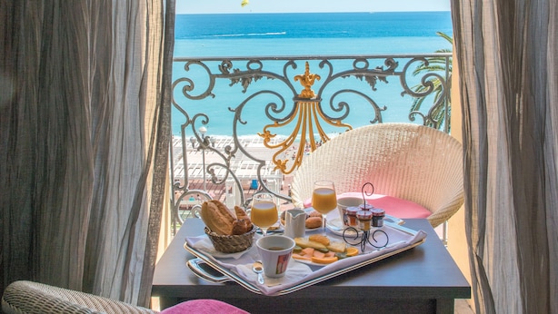 Un balcón con una mesa dispuesta para el desayuno, con vista al mar.