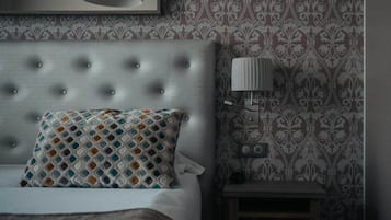 Una camera da letto con una testiera imbottita, un cuscino fantasia, una lampada da comodino e una decorazione a parete.