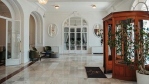 Un lobby espacioso con suelo de mármol, arcos y una mesa de recepción de madera.