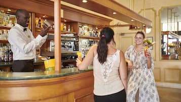 Un coin bar avec un barman, une femme tenant un verre et une autre femme avec un bouquet de fleurs.