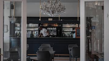 A bar area with a bartender, shelves of bottles, and bar stools.