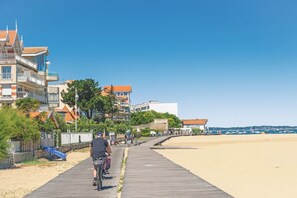 Une promenade en bois menant à une plage, avec des bâtiments et un ciel dégagé.