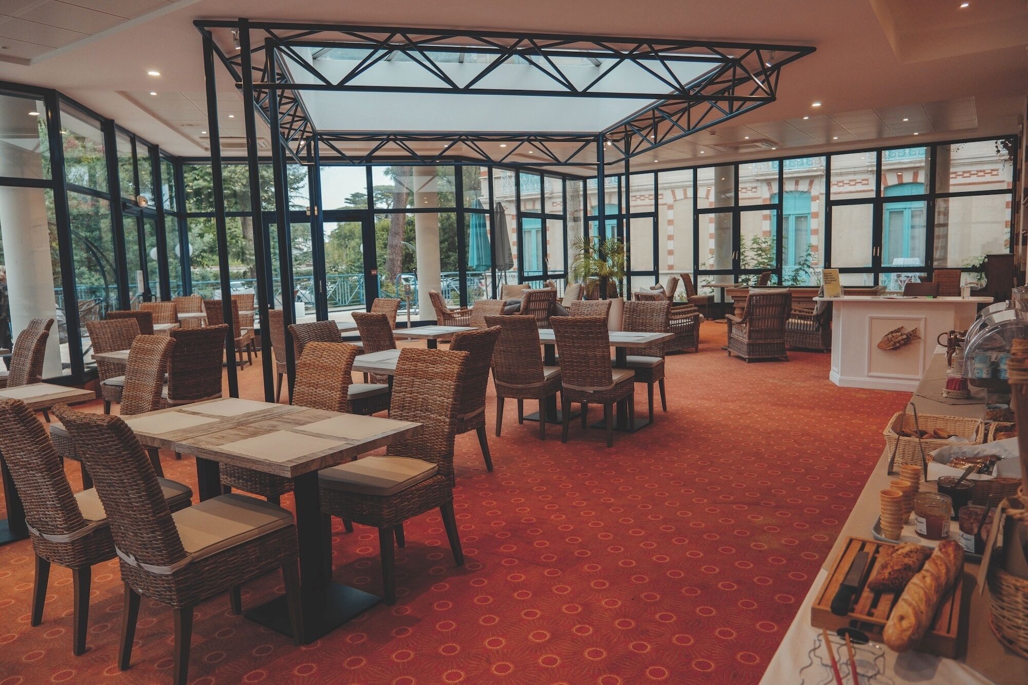 A spacious indoor area with wicker furniture, large windows, and a red carpet.