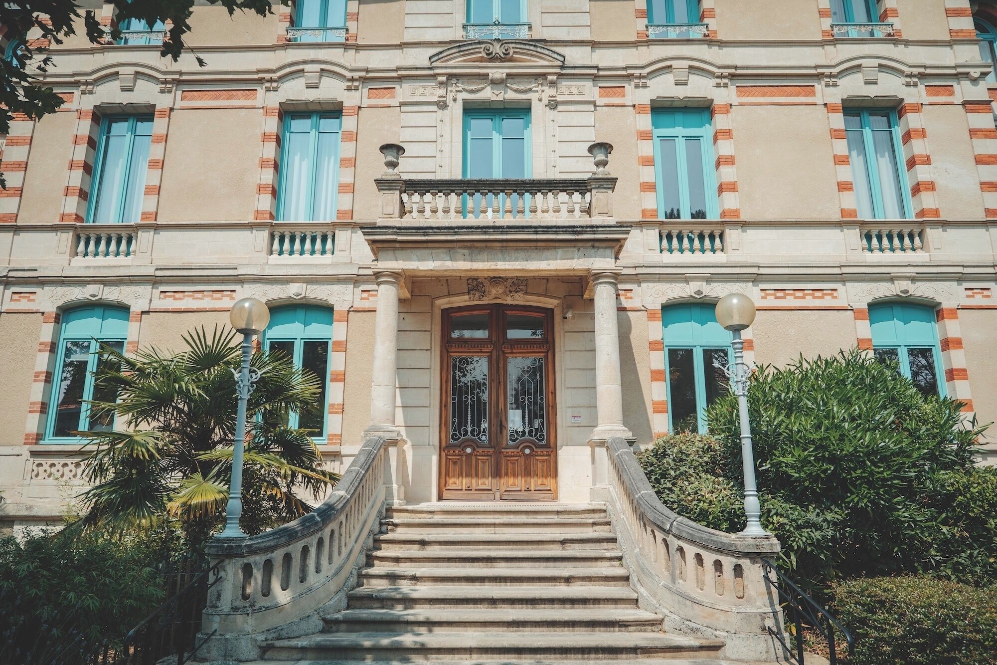 A multi-story building with a grand entrance, a staircase leading up to the entrance, and a balustrade.