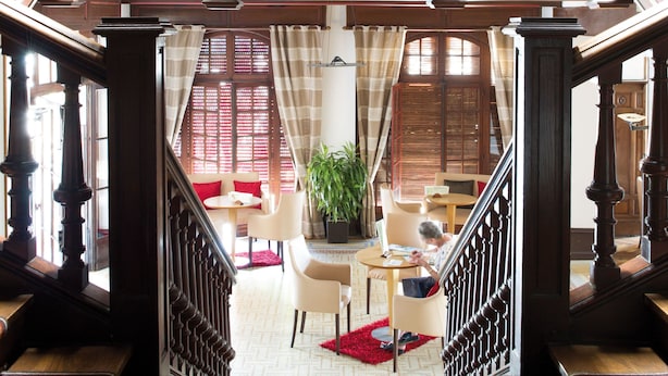 A grand staircase with wooden railings and a patterned carpet leading to a living area with a red rug, a plant, and a seating area. - Hôtel Résidence Vacances Bleues Orhoitza (Hendaye)