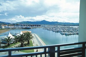 A marina with boats, a beach, and mountains in the background.