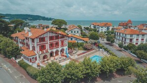 An aerial view of a coastal town with traditional architecture, a swimming pool, and a view of the sea. - Hôtel Résidence Vacances Bleues Orhoitza (Hendaye)