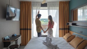 Ein Hotelzimmer mit Bett, Schreibtisch, Fernseher und Blick ins Freie.