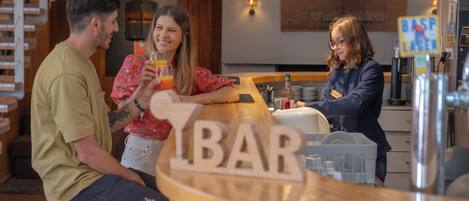 Un área de bar con mobiliario de madera y un cartel que dice 'BAR'.