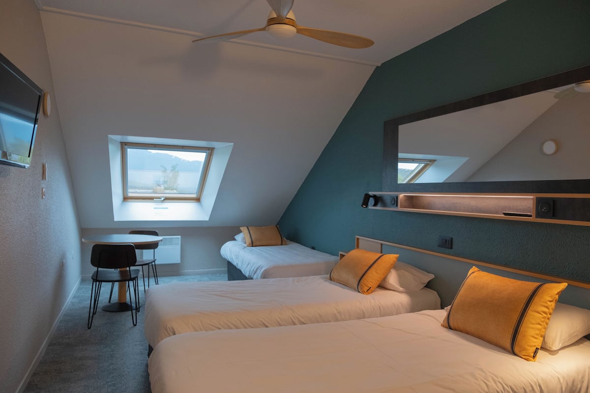 Een moderne hotelkamer met twee bedden, een bureau en een raam.
