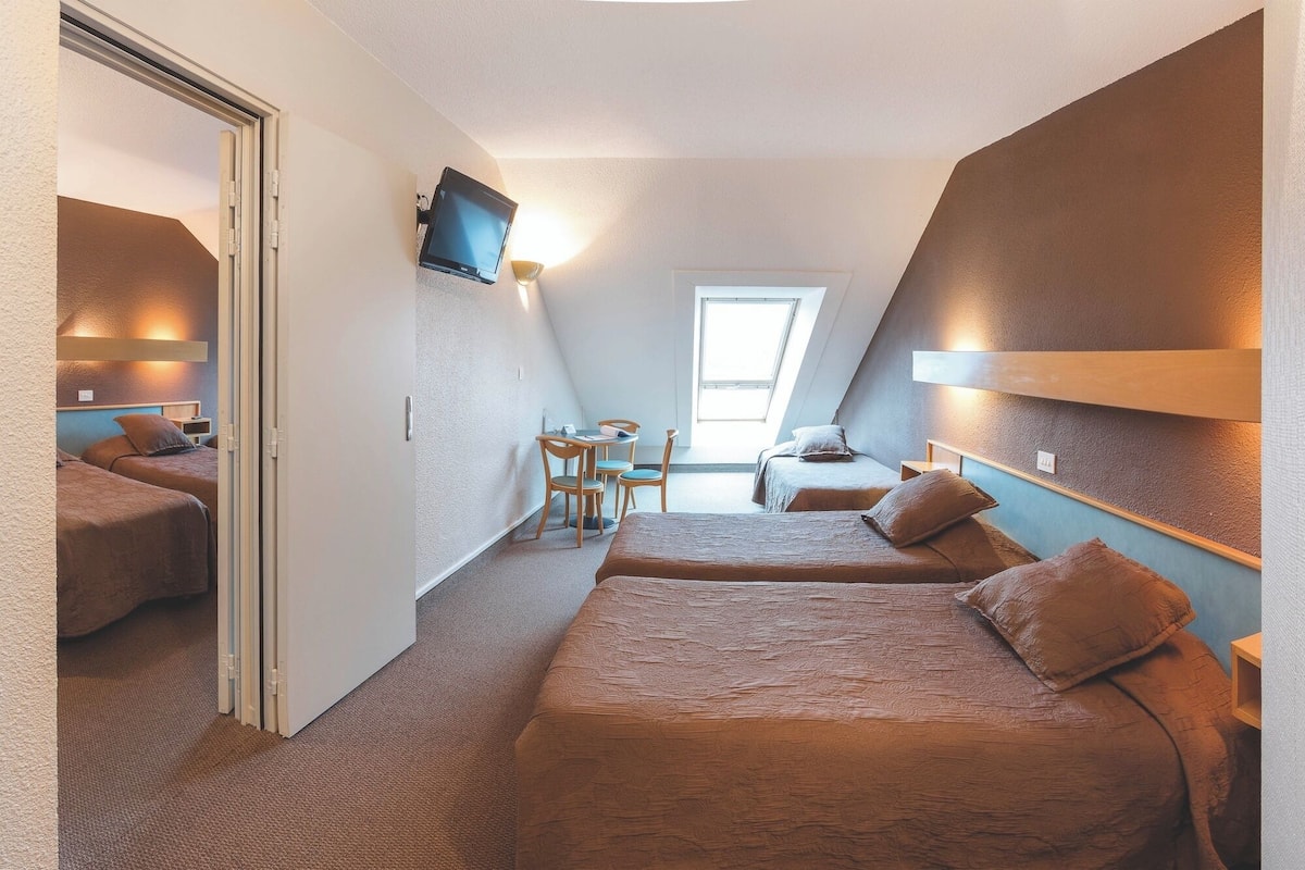 Een kleine kamer met twee bedden, een bureau en een tafeltje.