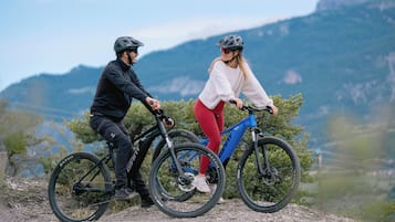 Two people on bicycles on a mountain trail with a clear view of the surrounding landscape.