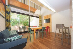 A modern interior with a dining area, a sofa, and a TV mounted on the wall.