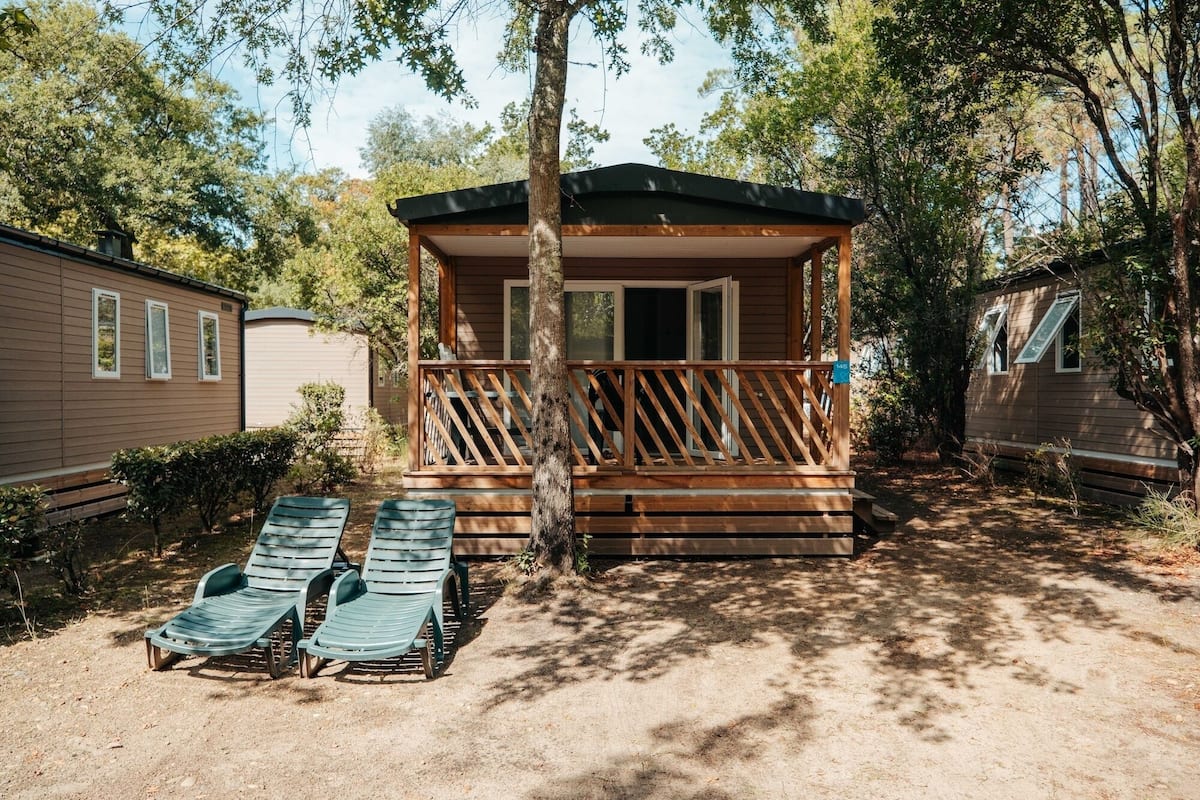 A small cabin with a wooden deck and two lounge chairs.