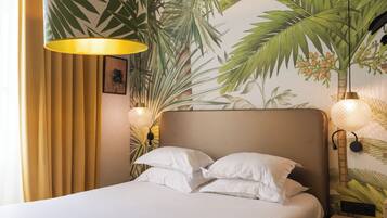 A hotel room with a bed, curtains, a wall mural, and two wall-mounted lamps.