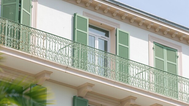 A building with a balcony, green shutters, and a street lamp. - Hotel Verlaine (Cannes)