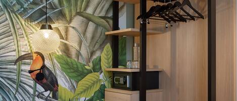 A modern room with a tropical mural, a wooden shelf unit, a hanging light fixture, and a small bedside table.