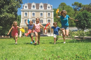 Un grupo de niños jugando en un césped, con un edificio grande al fondo.