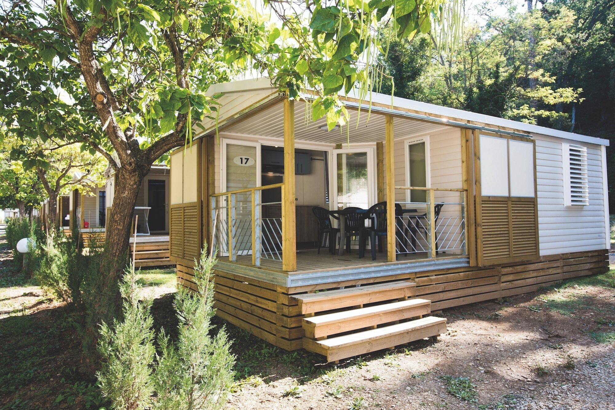 Ein Wohnmobil mit Veranda, Essbereich und kleiner Terrasse.