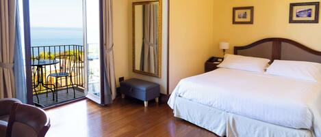 A hotel room with a balcony, a bed, a chair, and a small table.
