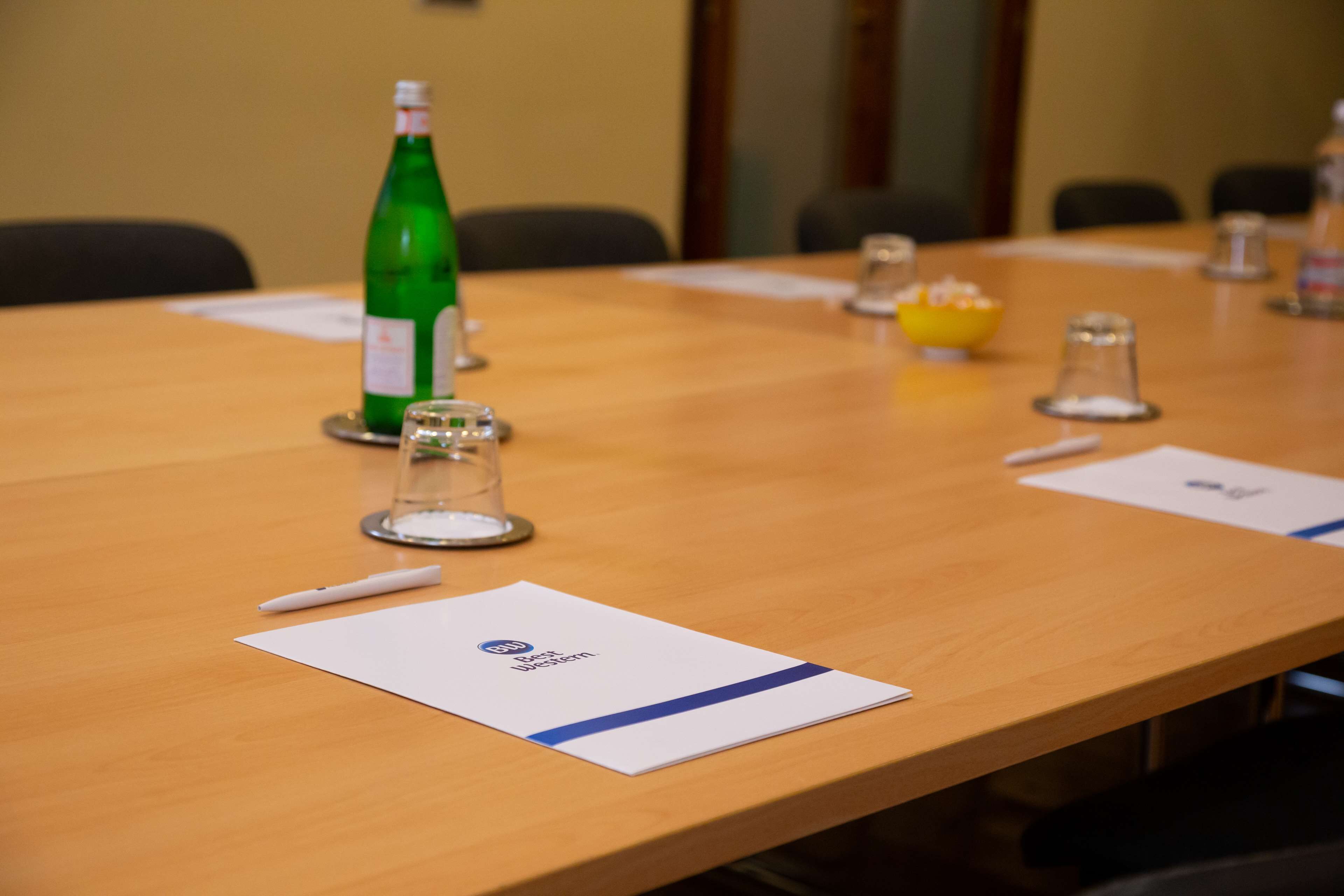 Una mesa de conferencias con documentos, un bolígrafo, un vaso y una botella.
