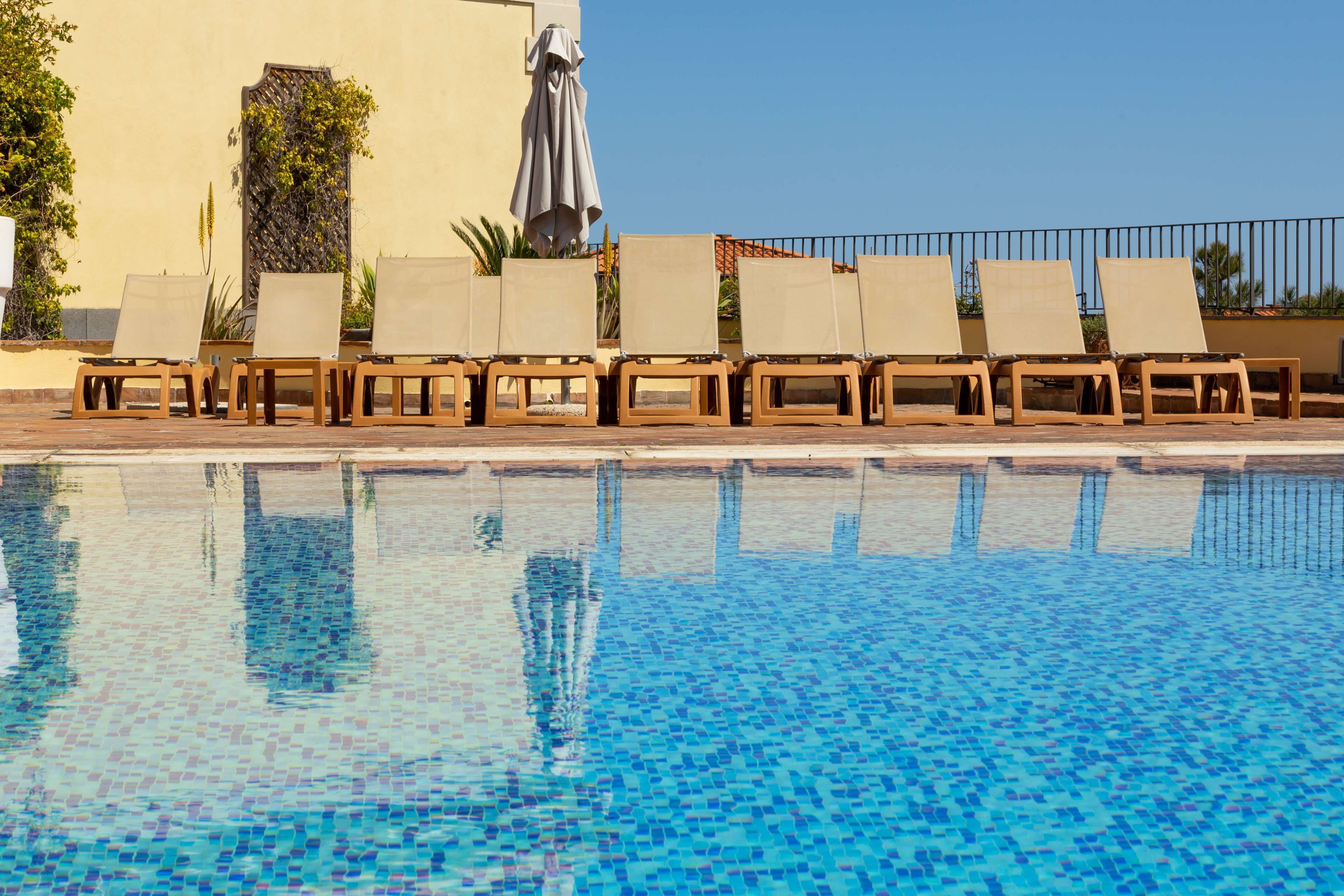 A pool with lounge chairs and a covered umbrella.
