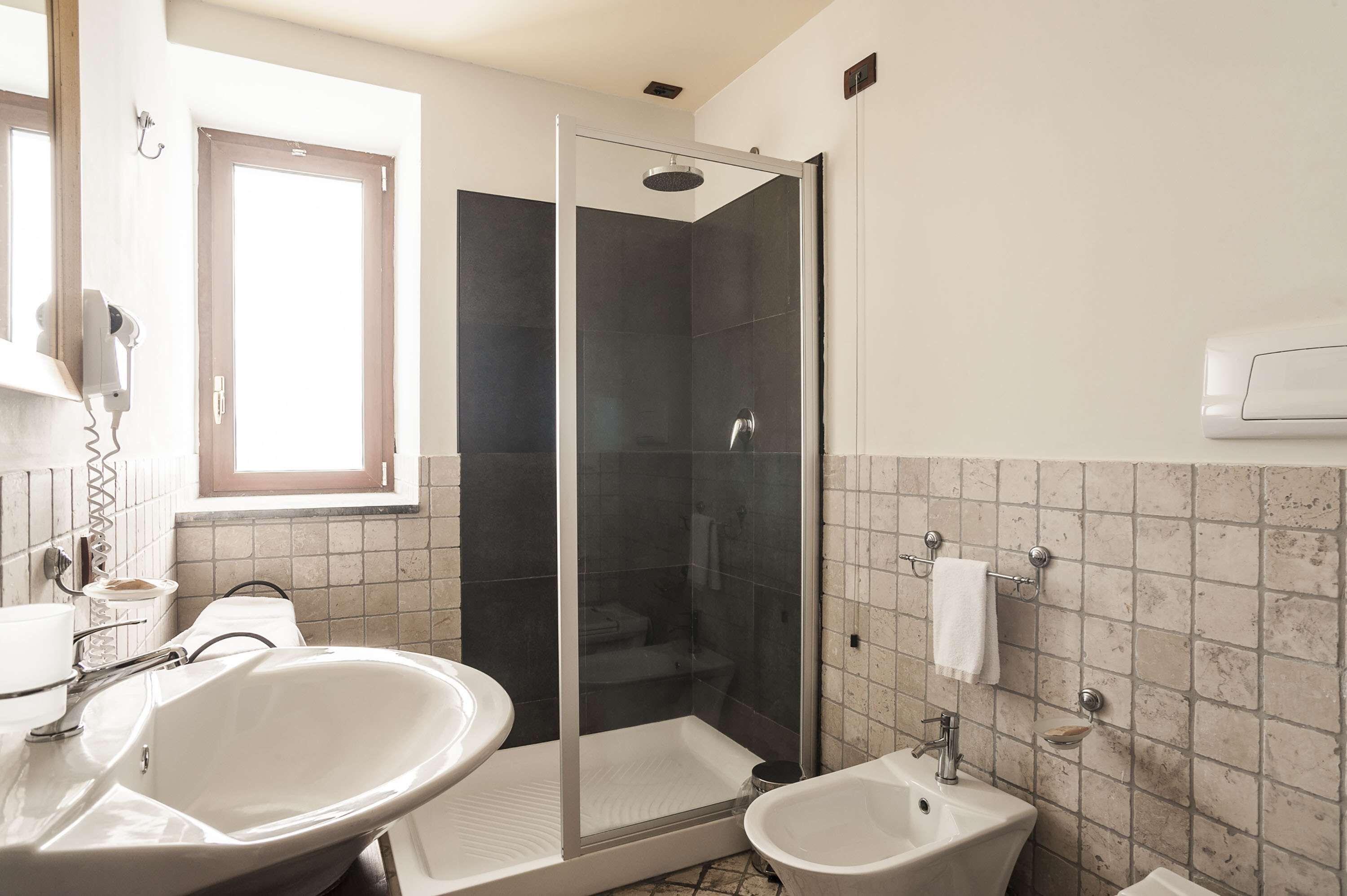 Une salle de bain dotée d’une douche à parois de verre, de deux lavabos et d’une fenêtre laissant entrer la lumière naturelle.